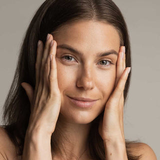 Woman with hands on face against a neutral background