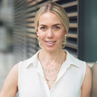Mrs Helen Dodd wearing a white sleeveless top with layered necklaces against a blurred background