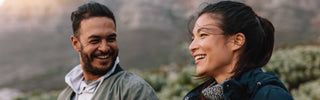 Two people smiling outdoors with a mountainous background