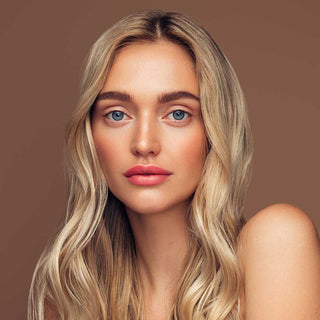 Woman with blonde hair and blue eyes against a brown background