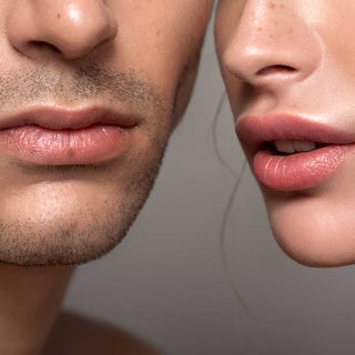 Close-up of a man and woman's lips against a neutral background