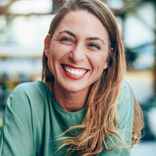 Woman with a bright smile wearing a green shirt outdoors