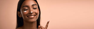 Woman applying skincare product on her face with a beige background